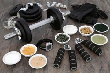 Weight training equipment for body builders with dumbbell weights, hand grippers, dietary food powder supplements, vitamin pills, heart rate monitor watch, leather gloves and tape measure.