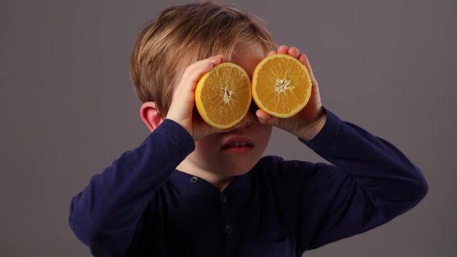 happy child looking through oranges for fresh vision or health