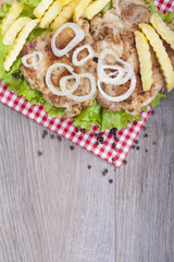  Grilled chicken drumstick on fresh lettuce,  fries and onions