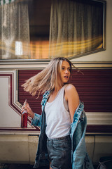 Young woman posing in front of the camper with drink 