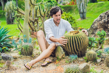 A man is sitting among large cacti. Pain concept