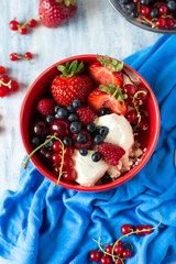 Healthy breakfast: cottage cheese with sour cream, strawberry, raspberry, blueberry, cherry and red currant on blue wooden table. Selective focus