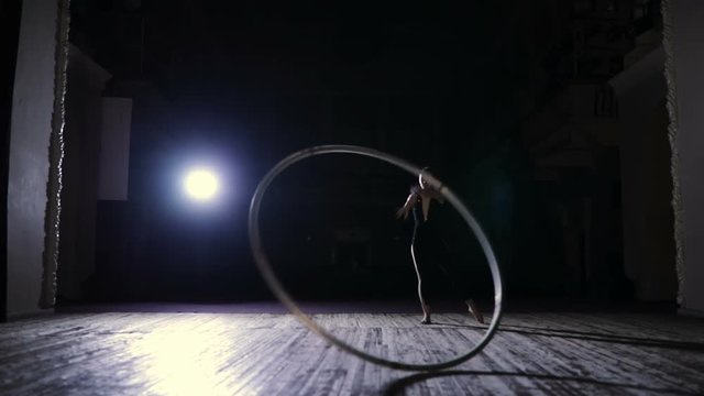 Circus artist training on stage with a cyr wheel