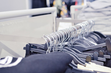 Closeup on shopping clothes hangers on rail in a designer store indoor background. Shallow depth of field of promotional marketing campaign department store design space