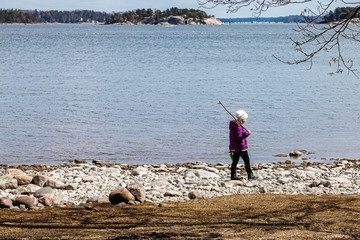 Fototapeta na wymiar A girl walks along the shore of the lake