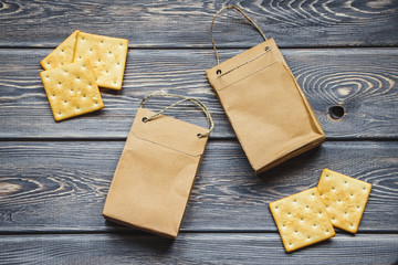 Kraft paper bags with biscuits on an old wooden table. Mockup of paper bags on a table. Flat lay. Top view.