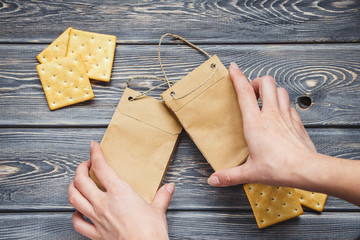 Kraft paper bags, biscuits with female hands on an old wooden table. Mockup of paper bags on a table. Flat lay. Top view.