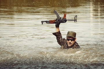 Action soldier in uniform swimming with assault rifle