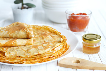 Thin russin pancakes on a plate on white wooden table. Healthy breakfast concept. close up.