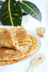 Thin russin pancakes on a plate on white wooden table. Healthy breakfast concept. close up.