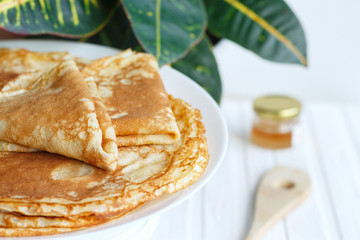 Thin russin pancakes on a plate on white wooden table. Healthy breakfast concept. close up.
