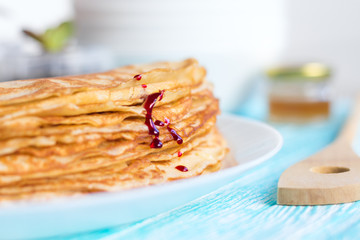 Thin russin pancakes with syrup on a plate on turquoise wooden table. Healthy breakfast concept. close up.