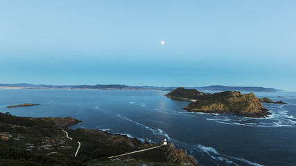 Aerial view of lighthouse cliffs sticking out of blue water of ocean in twilight of San Martiño Island in the Cies Islands, National Park Maritime-Terrestrial of the Atlantic Islands, Galicia, Spain