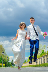 Naklejka premium Young and handsome newlyweds on a walk in the park. Jump into happiness