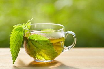 Cup of herbal tea with nettle on wooden background