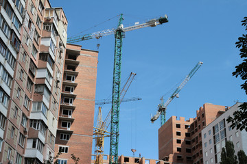 Building crane and building under construction against blue sky.