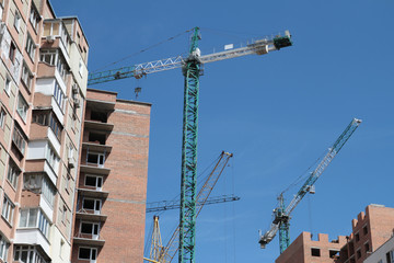 Building crane and building under construction against blue sky.