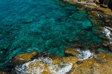 Crystal clear turquoise sea water background and rocky coast