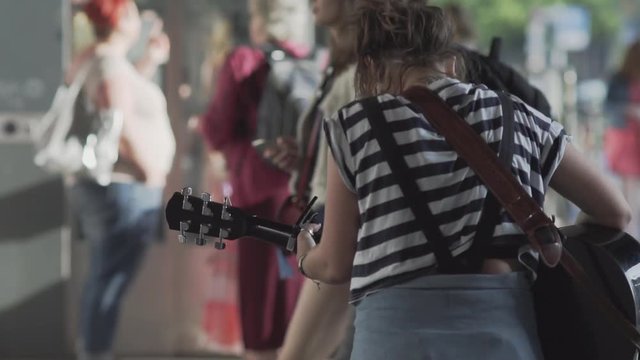 Unidentifiable Young Woman Playing Guitar On A Busy Shopping Street In Berlin In Summer. Slow Motion Shot