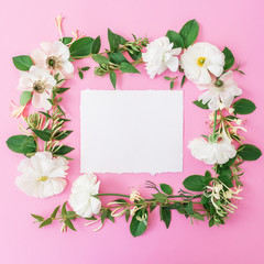 Floral frame made of white flowers and leaves on pink background. Floral background. Flat lay, top view.