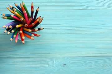 school and office supplies. school background. colored pencils in glass on blue wooden background. Top view with copy space.