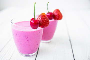 Cherry, strawberry milkshake and tasty berries on white table. Delicious cocktail