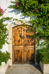 Fototapeta premium Cesme, Turkey - Old wooden door and bougainvillea plant