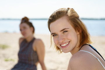 Fototapeta na wymiar Friendly young woman sitting on a sunny beach
