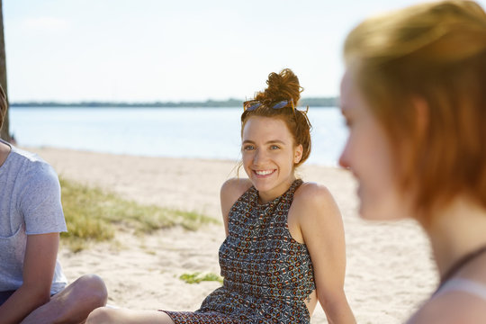 Smiling pretty young woman relaxing with friends by the sea