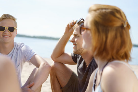 man sitting on a beach with friends on a hot sunny day
