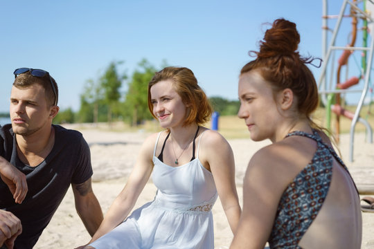 Three young friends sitting chatting on a beach