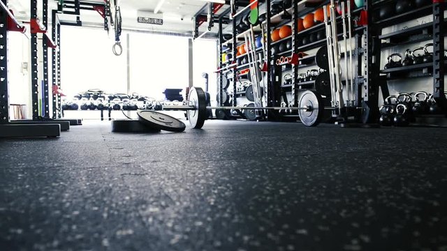 Metal heavy barbell laid on the floor in modern gym.