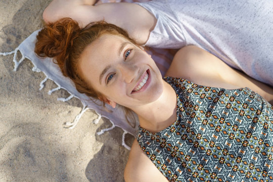 Happy relaxed young woman lying on a beach