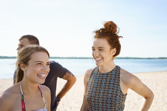 Laughing young women on the beach sharing a joke with her friends