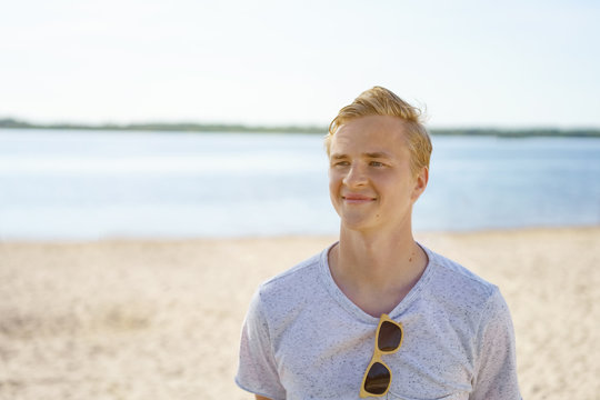 Handsome trendy young man relaxing on a beach