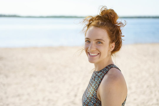 Attractive young redhead woman standing on a beach