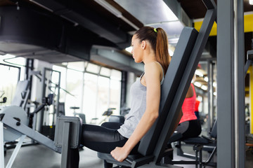 Fototapeta na wymiar Young women exercising on machine in gym