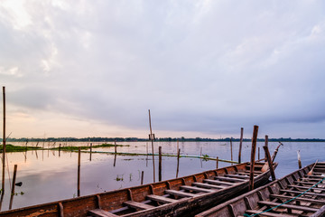 Naklejka premium Old wooden boat floating on the water amidst the natural landscape of the morning at Kwan Phayao Lake in Phayao Province, Thailand