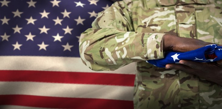 Composite image of mid section of soldier holding american flag