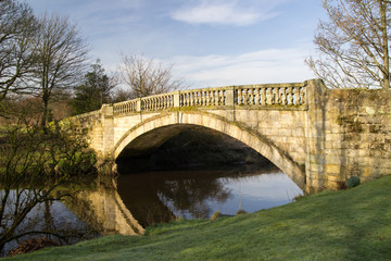 Fototapeta na wymiar Reflections near Stone bridge over White Cart Water in Pollok Country Park, Glasgow, Scotland.