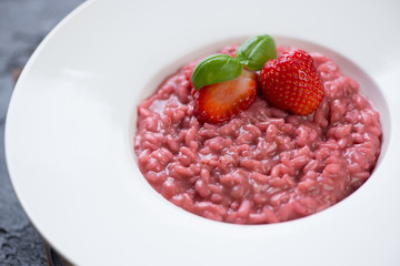 Close-up of risotto with strawberries in a white plate, selective focus, studio shot