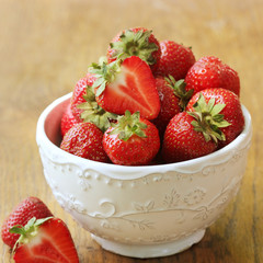 Fresh strawberries in bowl on wood table, organic garden berries