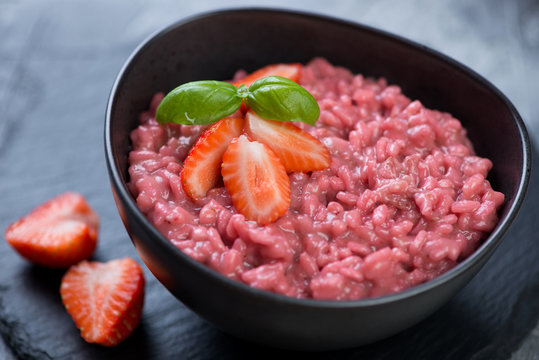Risotto with strawberries served in a black bowl, selective focus, close-up