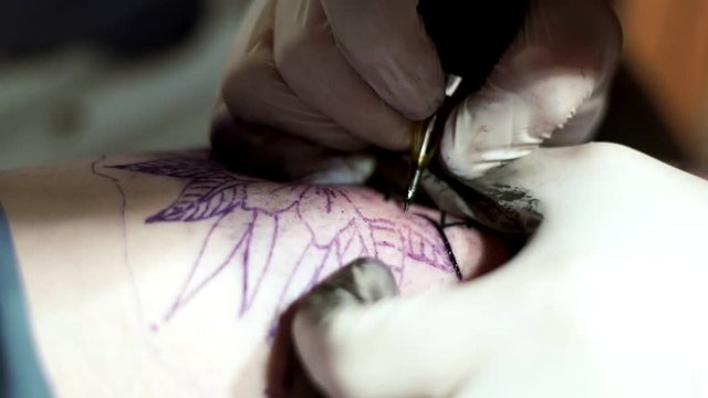 Tattooist does tattoo a client with a tattoo machine