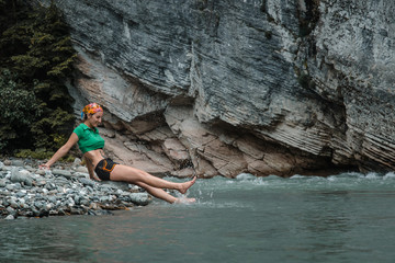 Fototapeta na wymiar tourist girl sitting in a mountain river