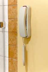 White plastic phone on a wall for emergency call or support.