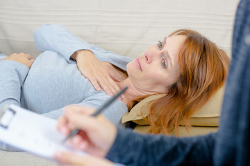 Naklejka premium sad woman sitting with therapist on sofa at home