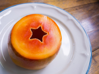 A half of papaya on white dish. Star sign.