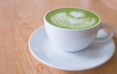 Hot green tea mutcha latte in white cup on wooden table