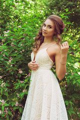 Pretty woman enjoying smell flowers. Portrait of young beautiful woman posing among blooming trees